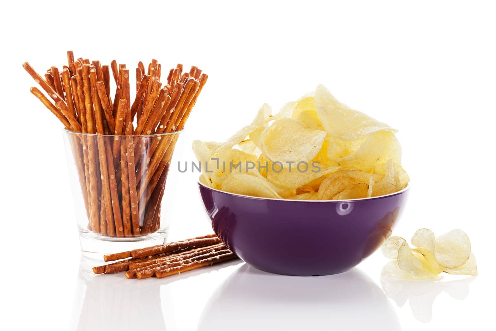 Chips and pretzel sticks on white background