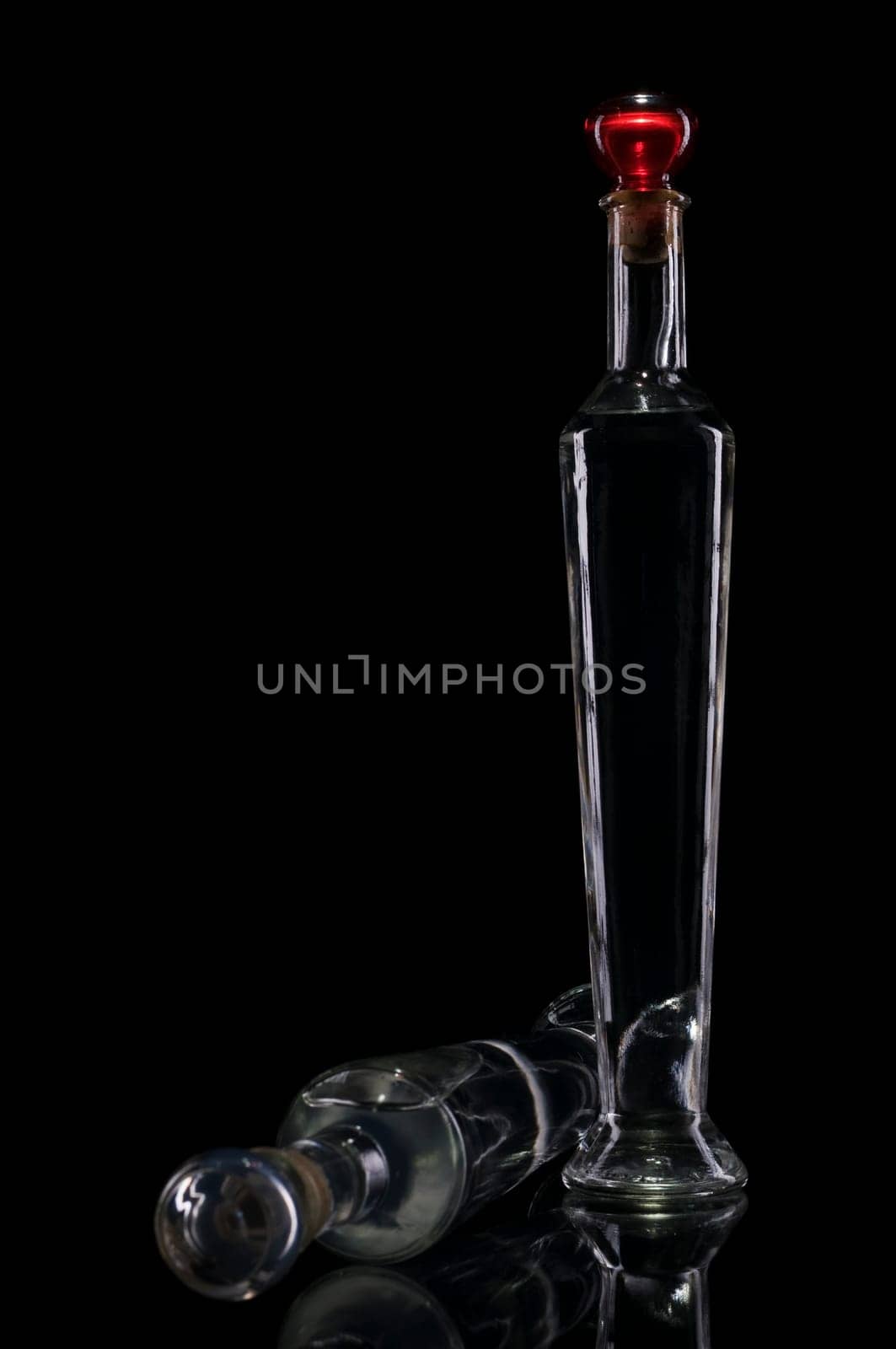 Studio shot of two narrow decorative bottles in front of black background with edge light