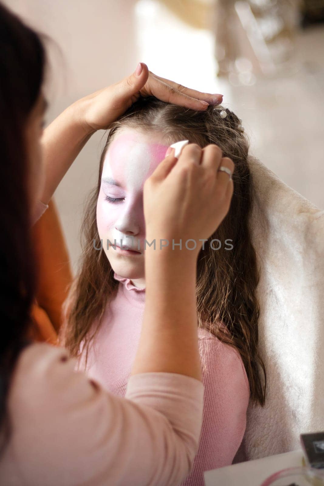 childrens makeup face paint drawings Girls face painting. Little girl having face painted on birthday party. closed eyes. High quality photo