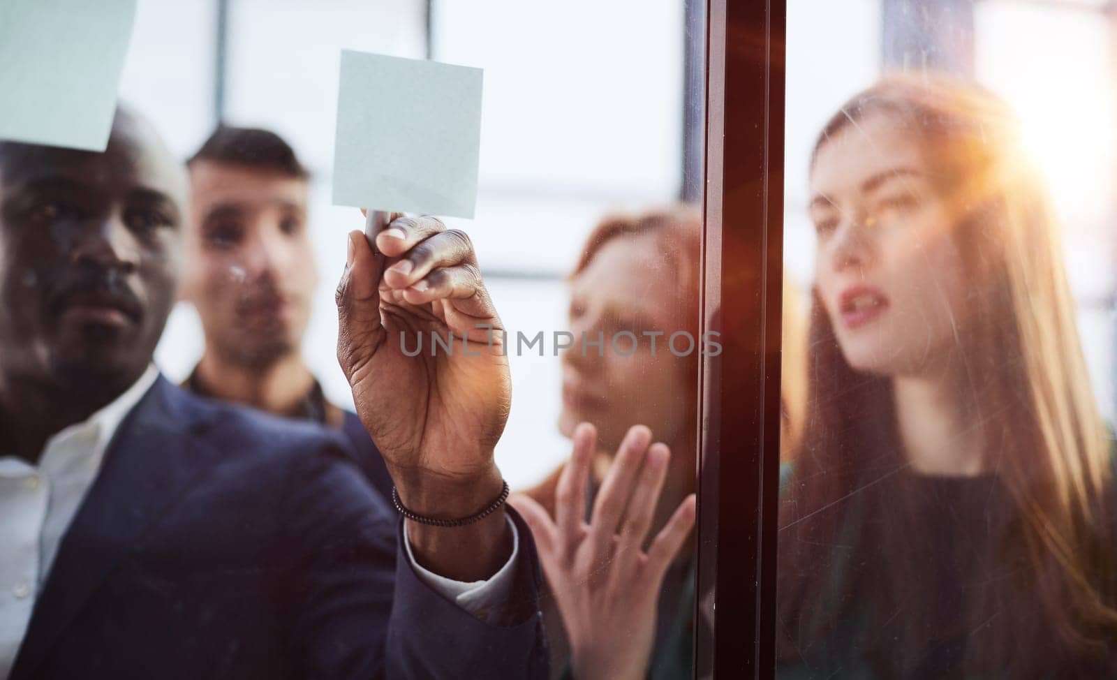 Creative business team looking at sticky notes on glass window