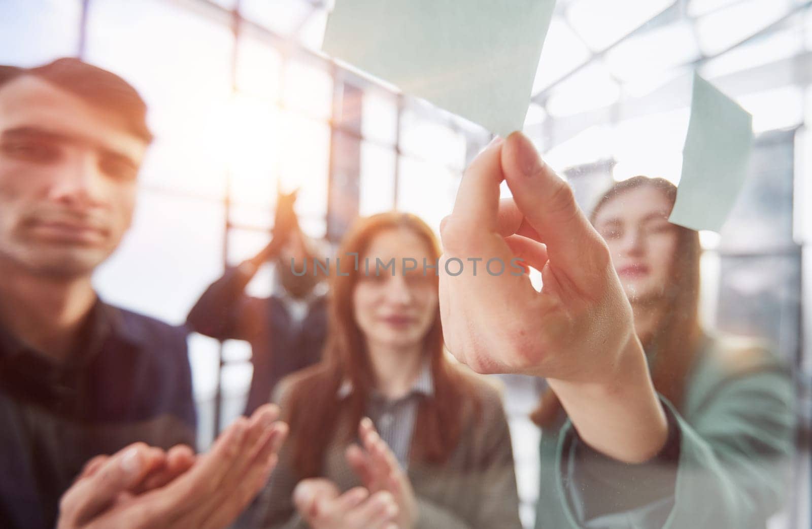 Creative business team looking at sticky notes on glass window