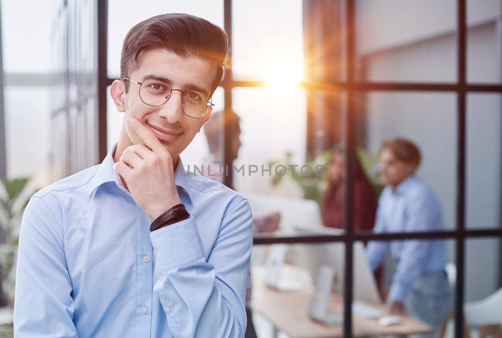 Handsome thinking young businessman in the office by Prosto