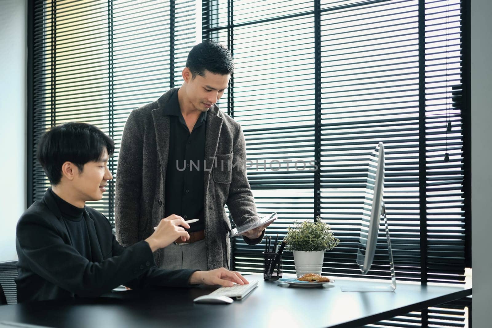 Startup business colleagues using digital tablet, discussing financial market data in modern office.