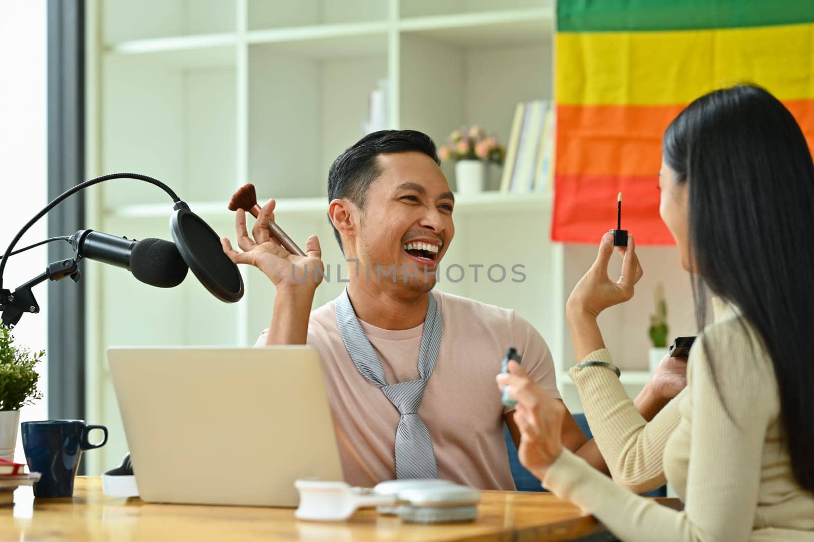 Joyful Asian gay man and friend recording podcast from home studio. Radio, podcasts and blogging concept by prathanchorruangsak