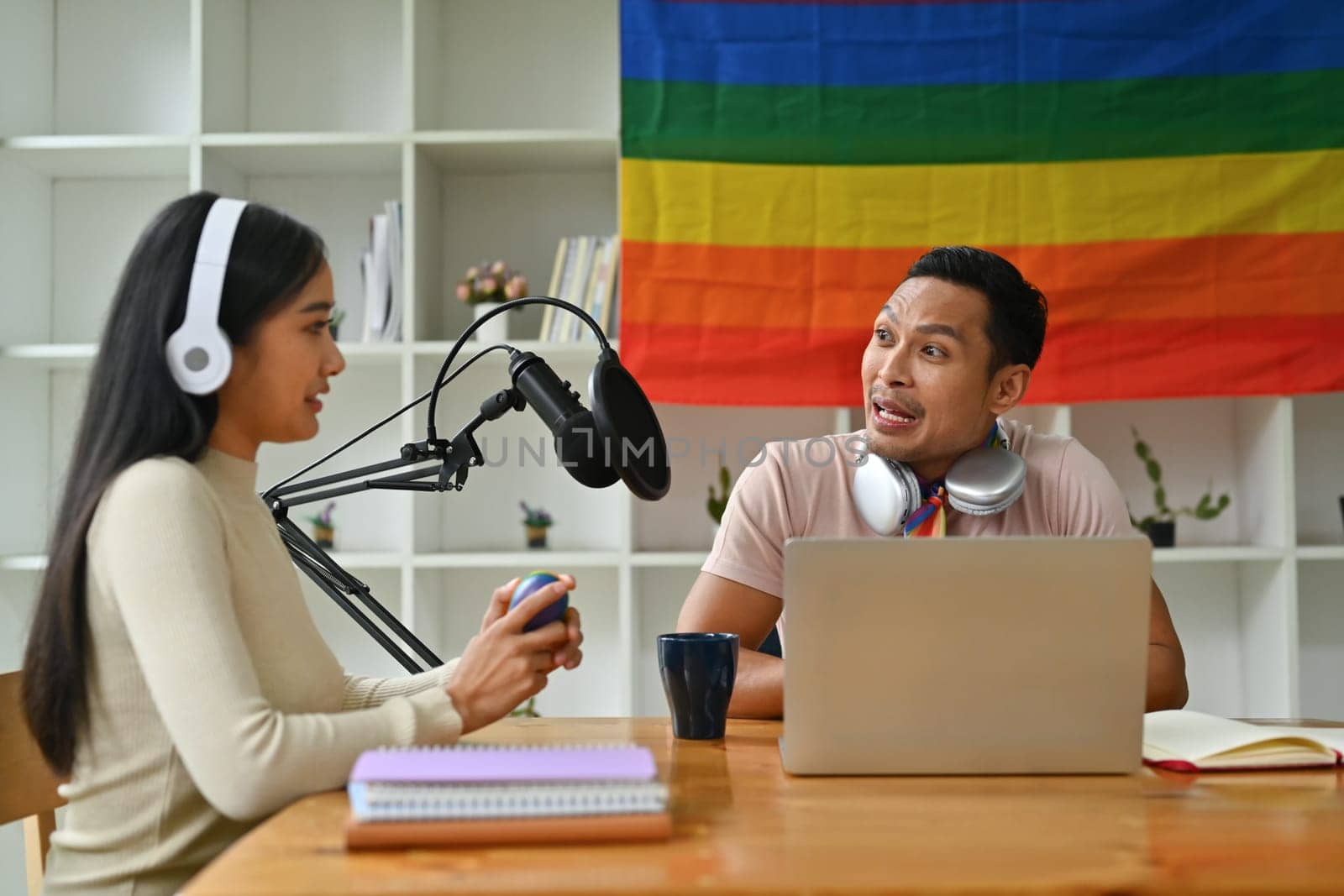 Handsome gay man radio host interviewing guest in studio while recording live podcast in studio by prathanchorruangsak