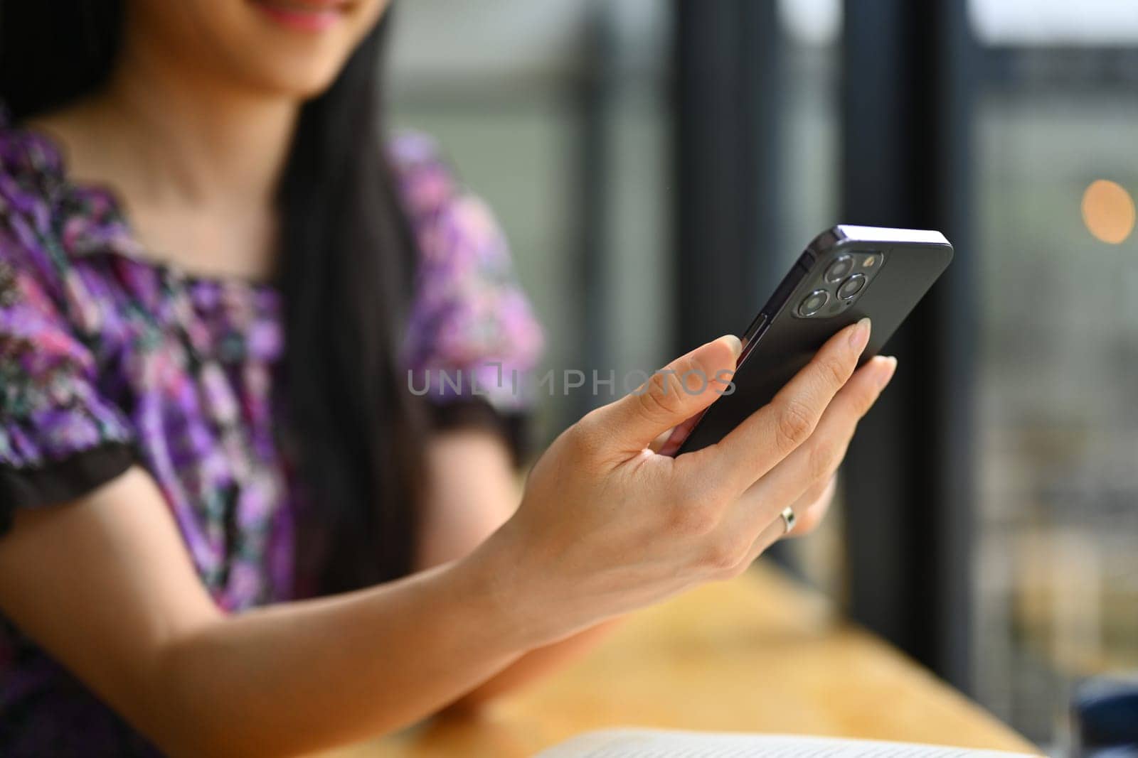 Cropped shot of young woman texting message, communicating online on mobile phone.