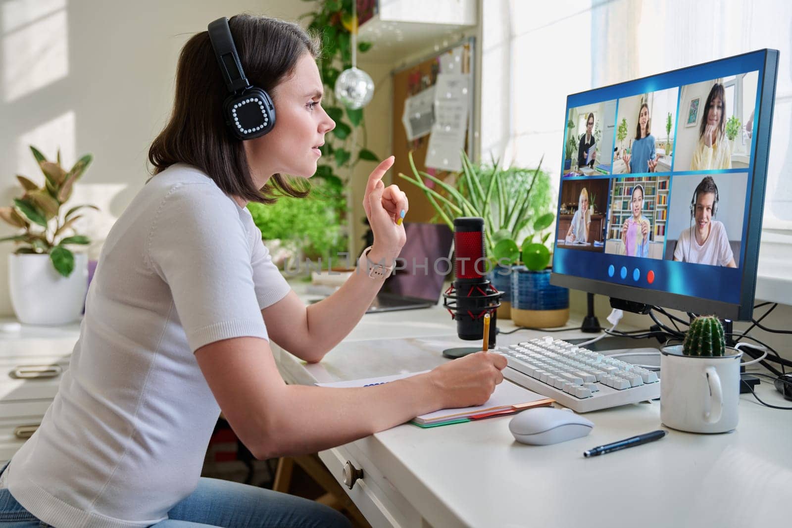 Young female teacher looking at computer screen at home online lesson with group of teenage students. Distance learning virtual remote class course interactive online lesson video conference call chat