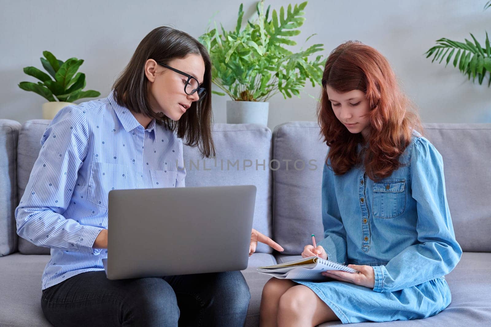 Preteen girl studying together with the teacher, in the office on the couch