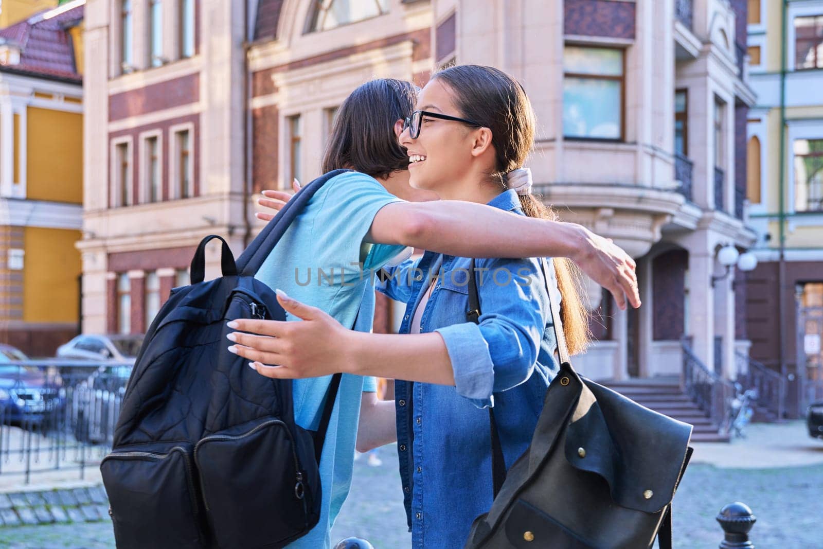 Meeting, hugging teenage male and female friends on the city street. Fashionable having fun teenagers guy and girl together. Friendship, communication, holidays, lifestyle, youth, urban style