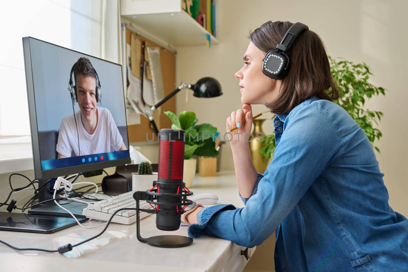 Female teacher in headphones teaching teen male student online. Sitting at home, high school teenage pupil at computer screen, talking female using video call chat conference. E-learning, remote lesson