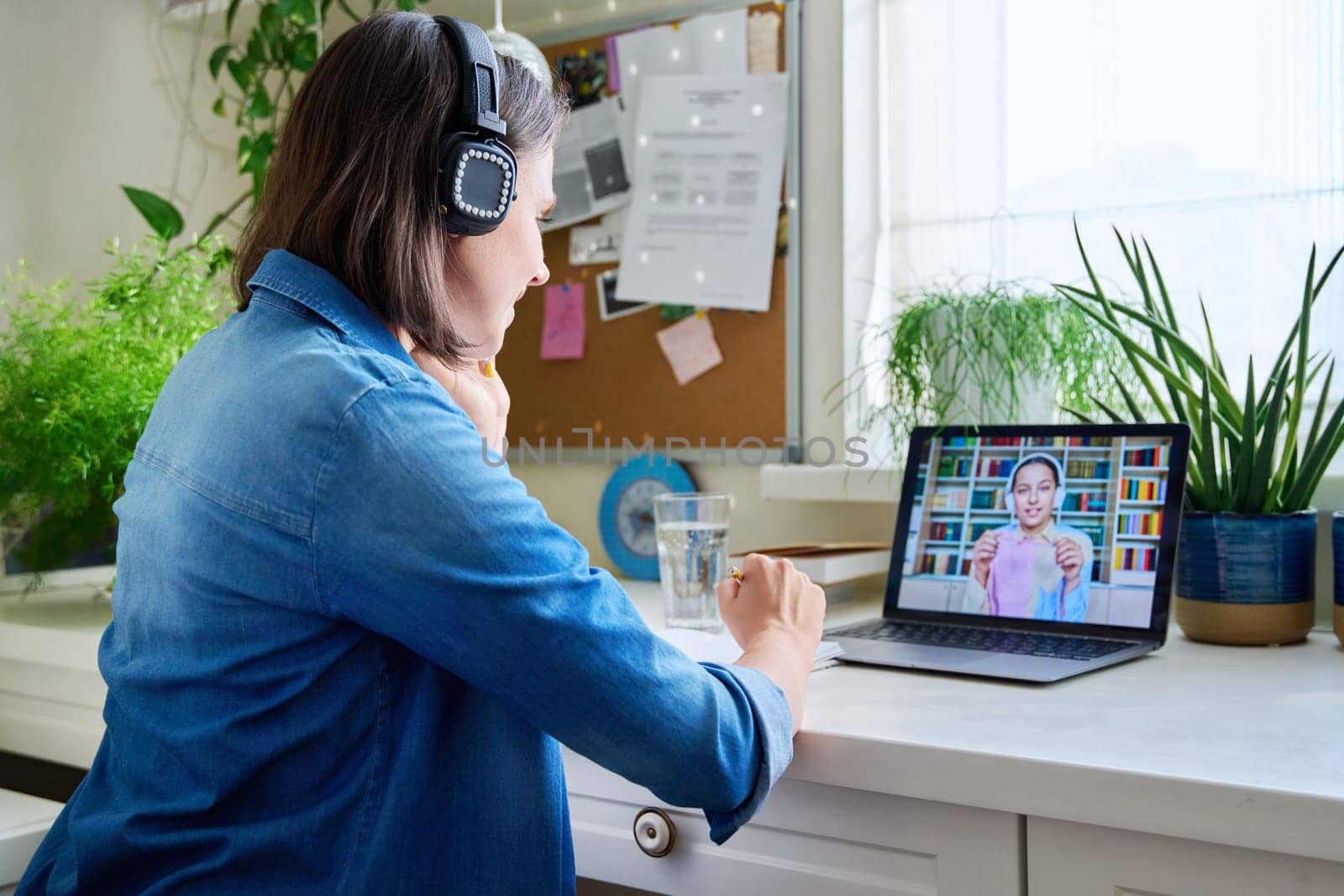 Young female teacher in headphones having video conference call with teenage girl student using laptop home. Online lesson e-learning distance remote classes technology in education knowledge school