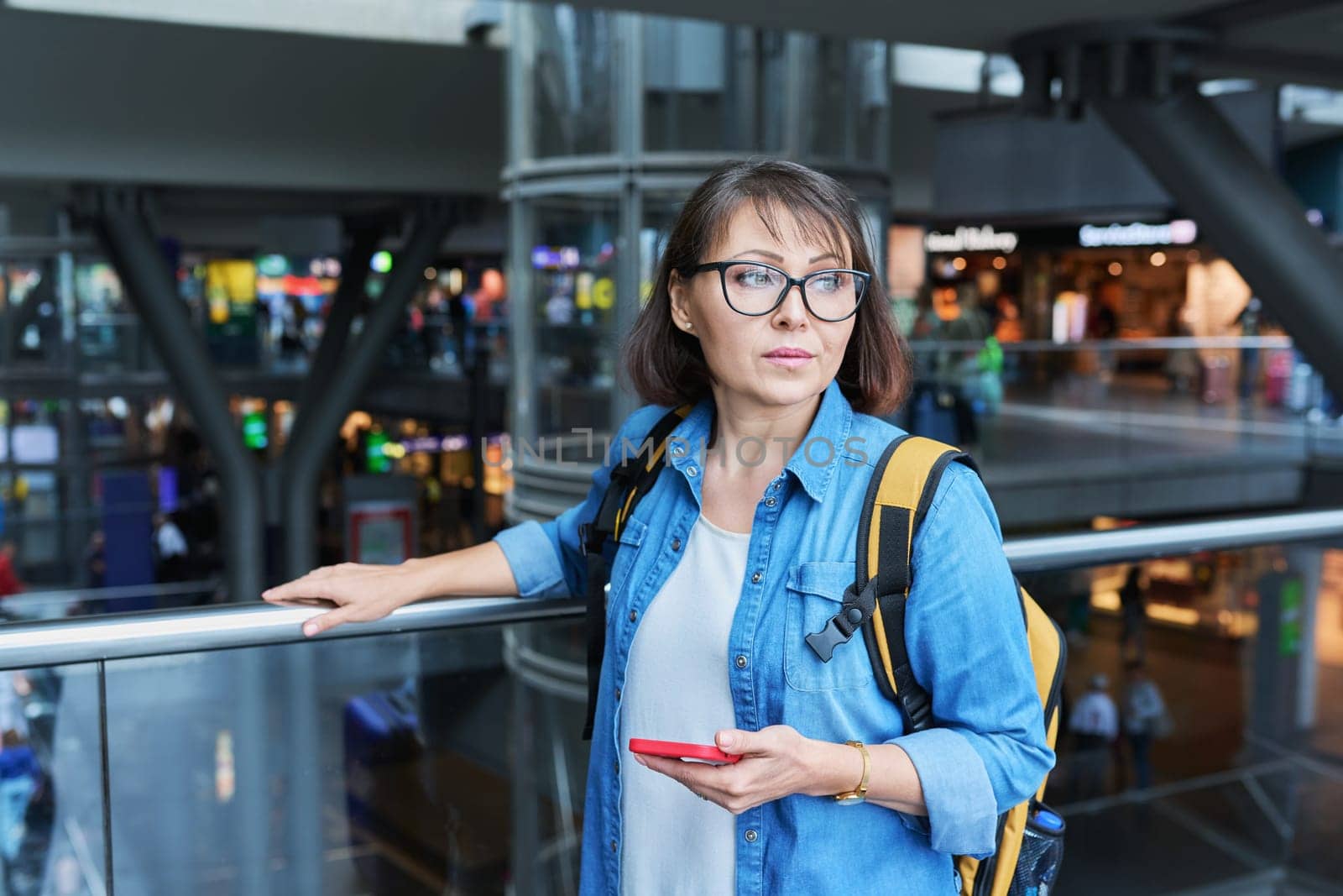 Woman on in modern building of city transport station with smartphone. Female using fast internet connection network for online ticketing service mobile application timetable transport route