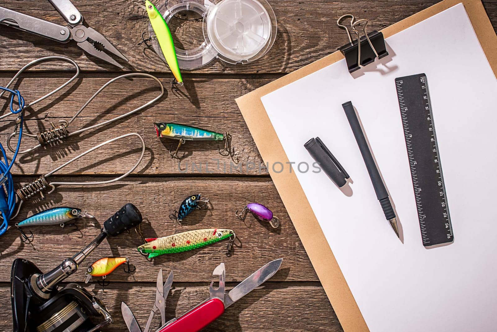 Accessories for fishing on the background of wood. Reel, fishing line, float, net hooks, lures for fishing. Top view. Still life. Copy space