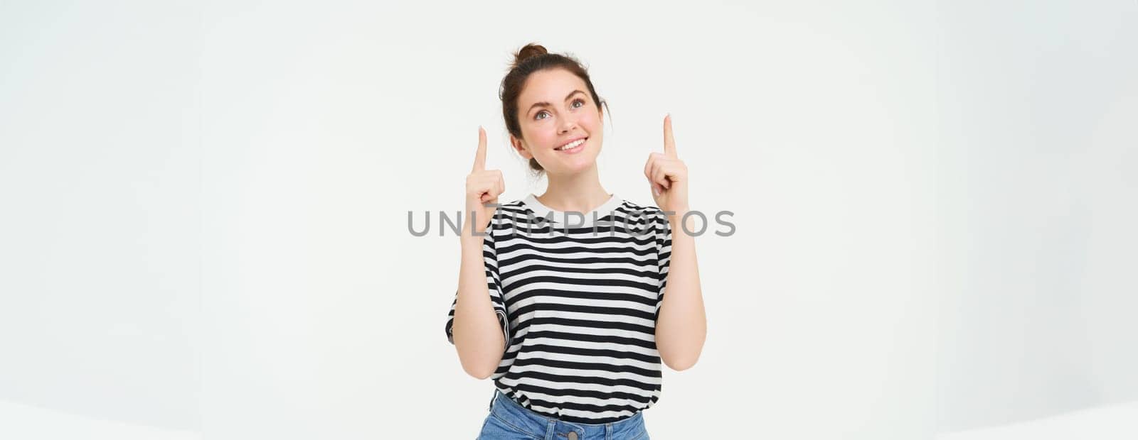 Advertising and lifestyle concept. Smiling cute woman pointing fingers up, showing advertisement, banner on top, standing over white background.