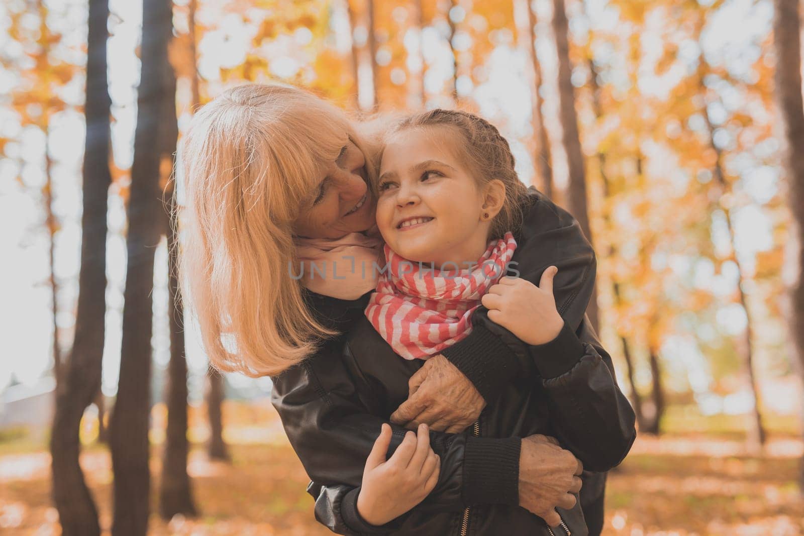 Grandmother with granddaughter in autumn park. Generations and family concept