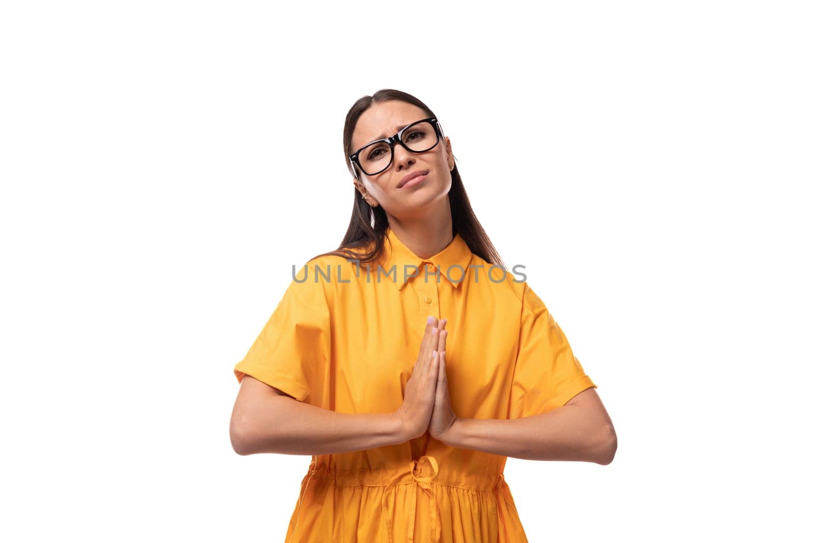 European young brunette lady dressed in an orange summer dress looks calm.