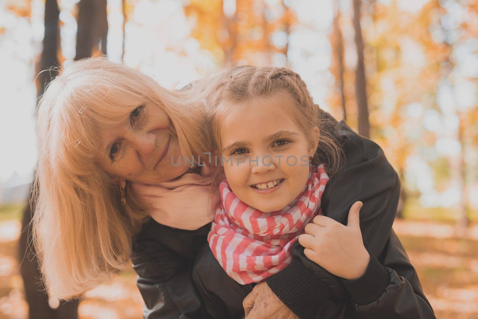 Grandmother with granddaughter in autumn park. Generations and family concept