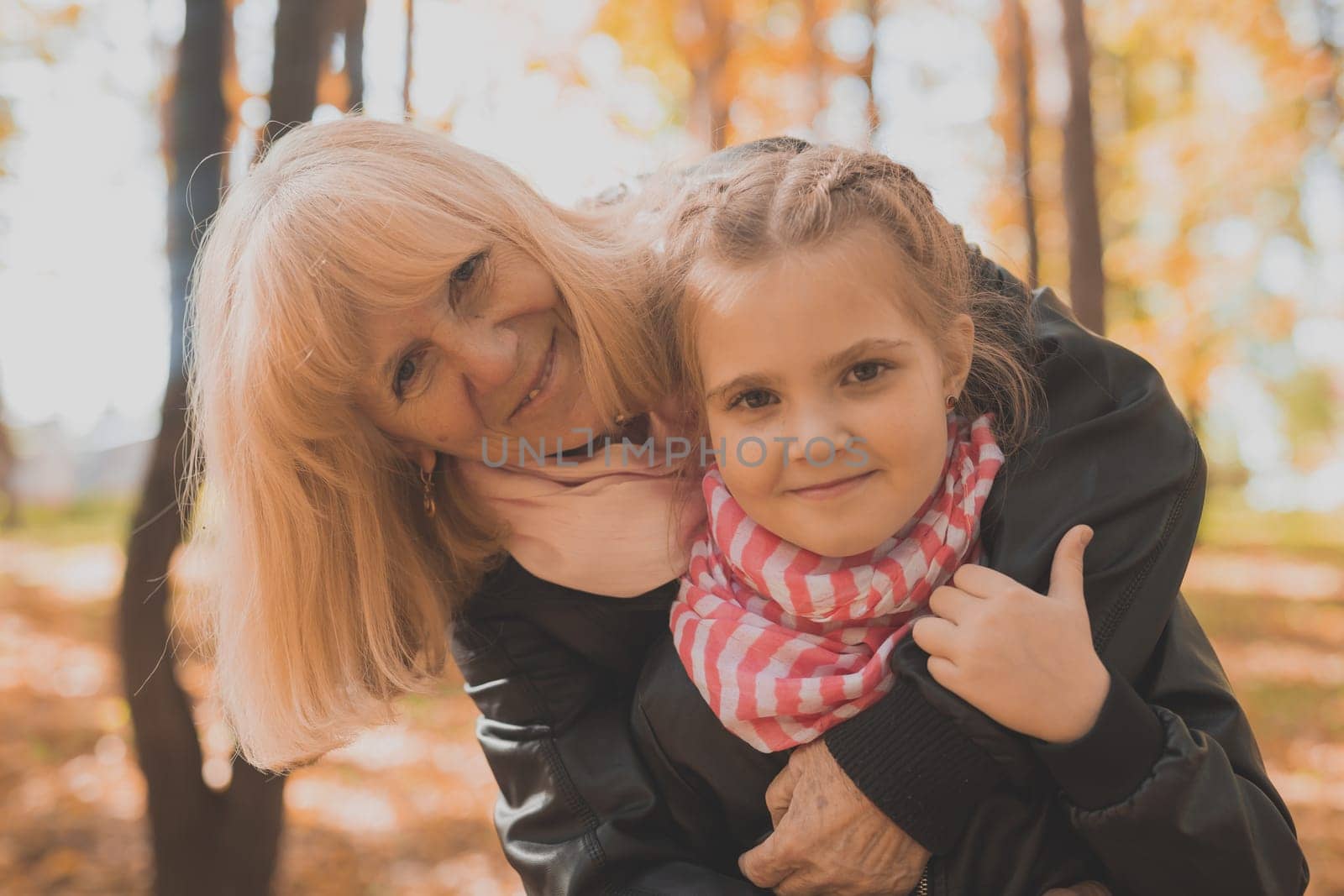 Grandmother with granddaughter in autumn park. Generations and family concept