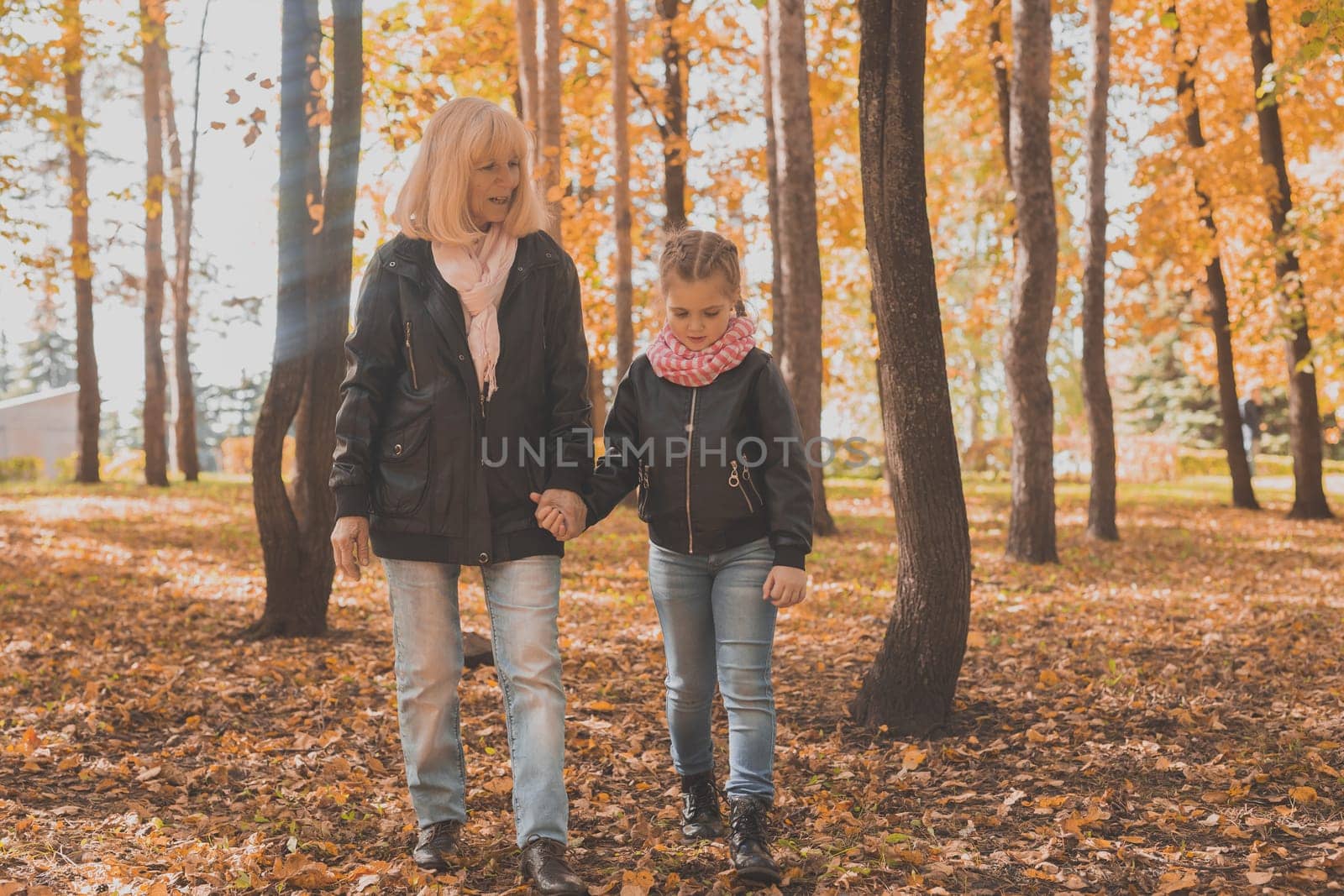 Grandmother with granddaughter in autumn park. Generations and family concept