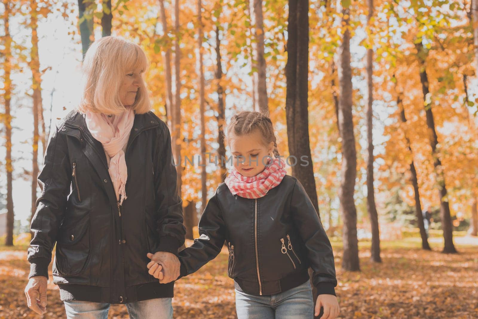 Grandmother with granddaughter in autumn park. Generations and family concept