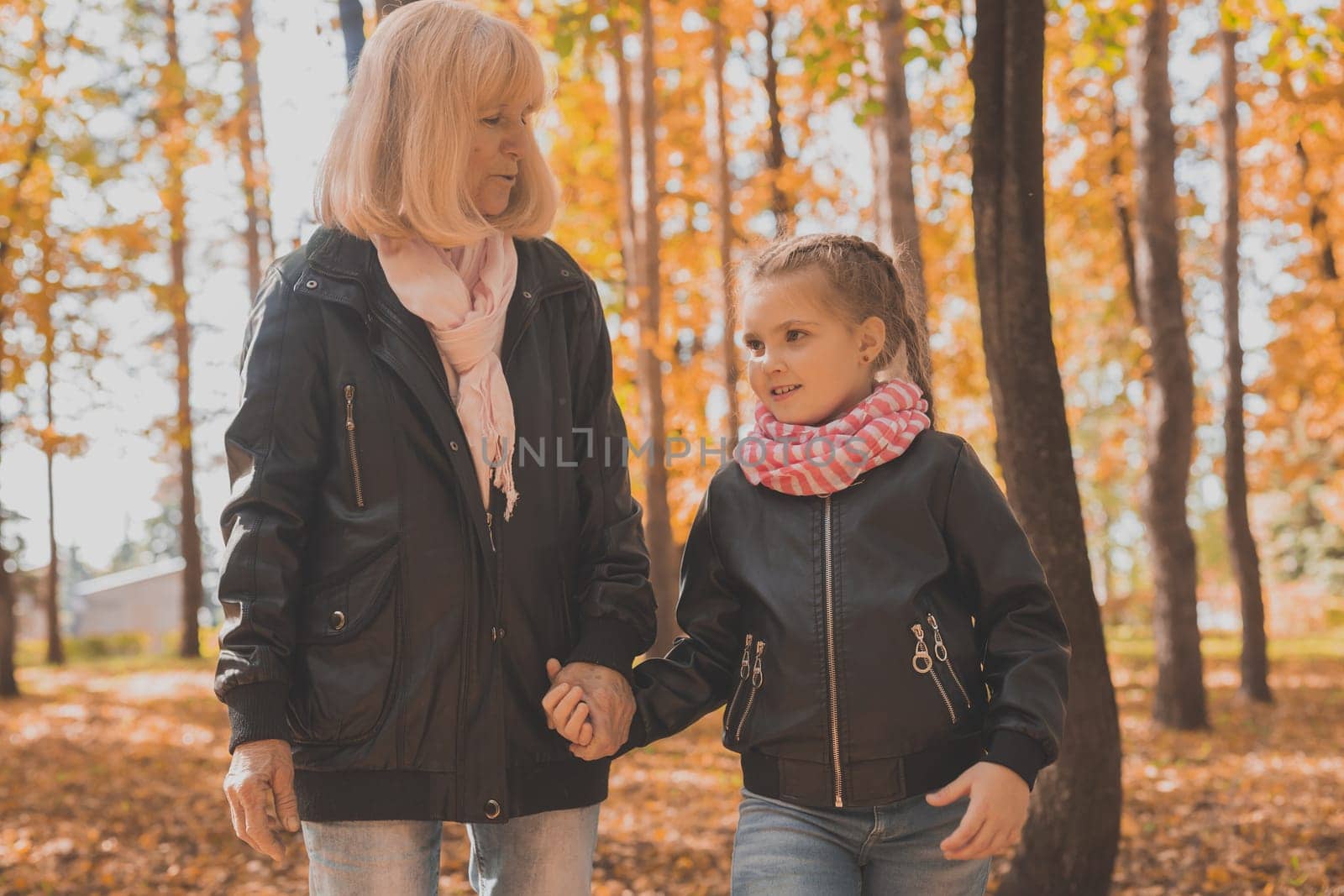 Grandmother with granddaughter in autumn park. Generations and family concept