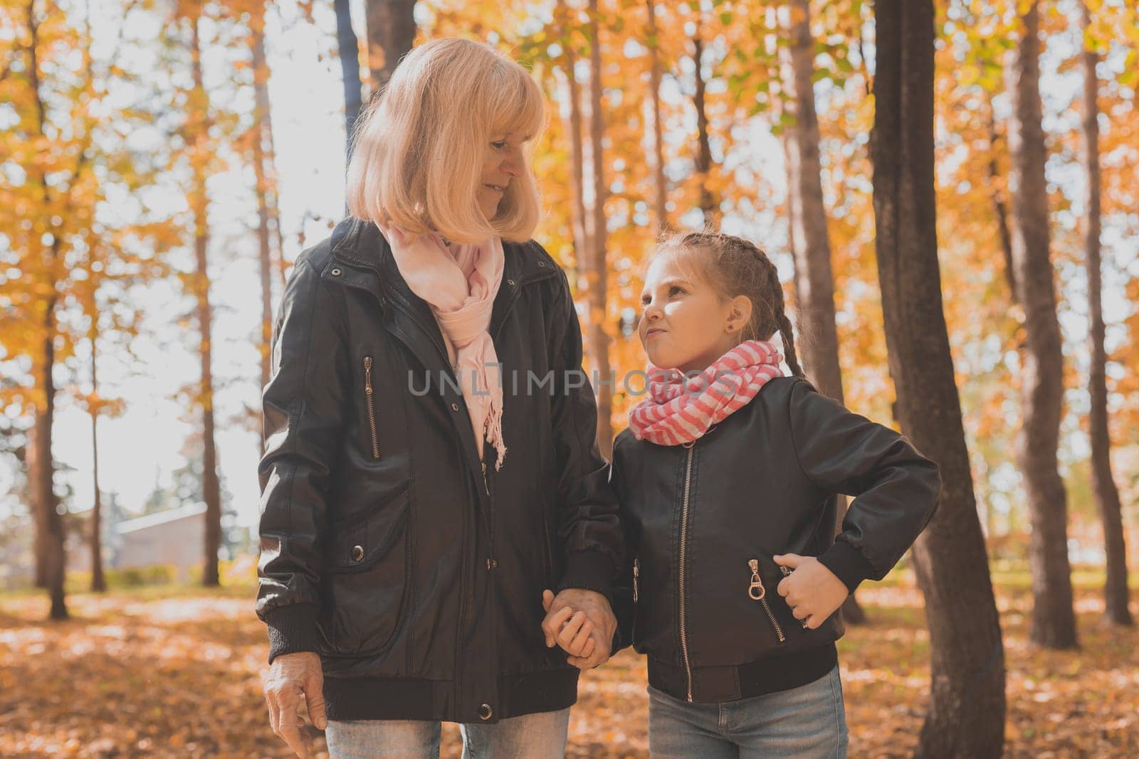 Grandmother with granddaughter in autumn park. Generations and family concept