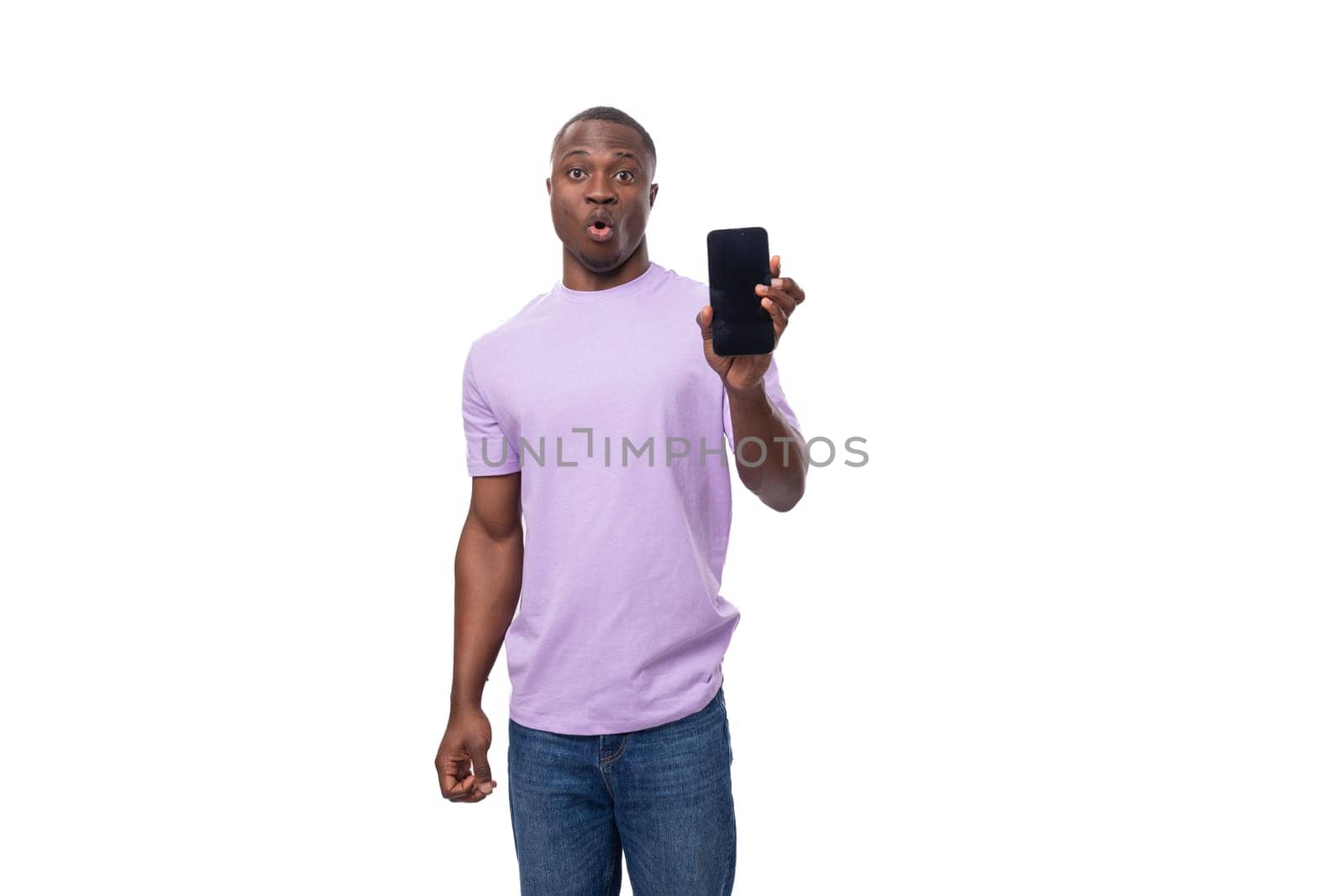 young smart african man dressed in a lilac t-shirt and jeans uses a smartphone.