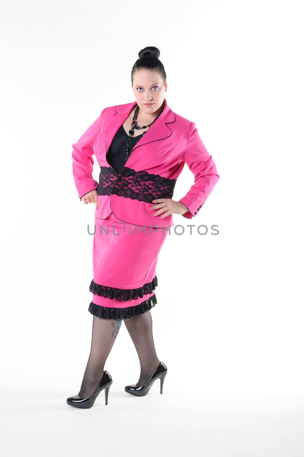 An adult overweight woman with a severe bun presented proudly in a pink costume. Isolated against white background.