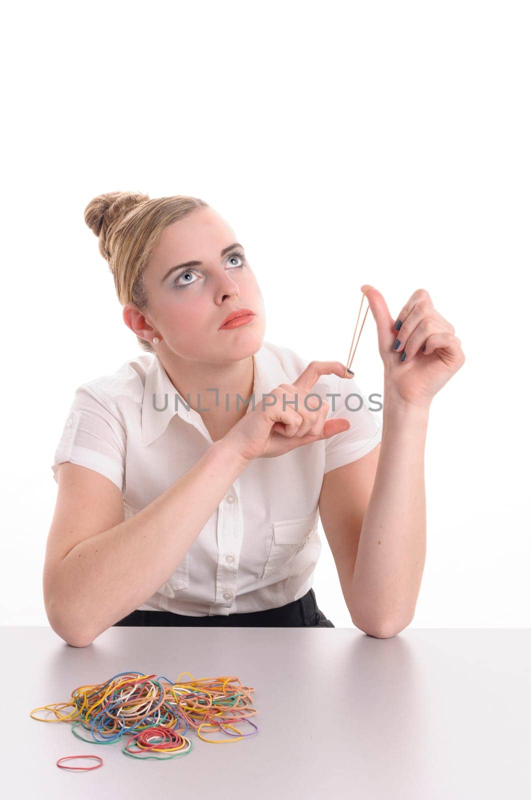 Young woman with blond hair wearing a business suit and has bored in the office, she plays with a rubber band, isolated against white background.