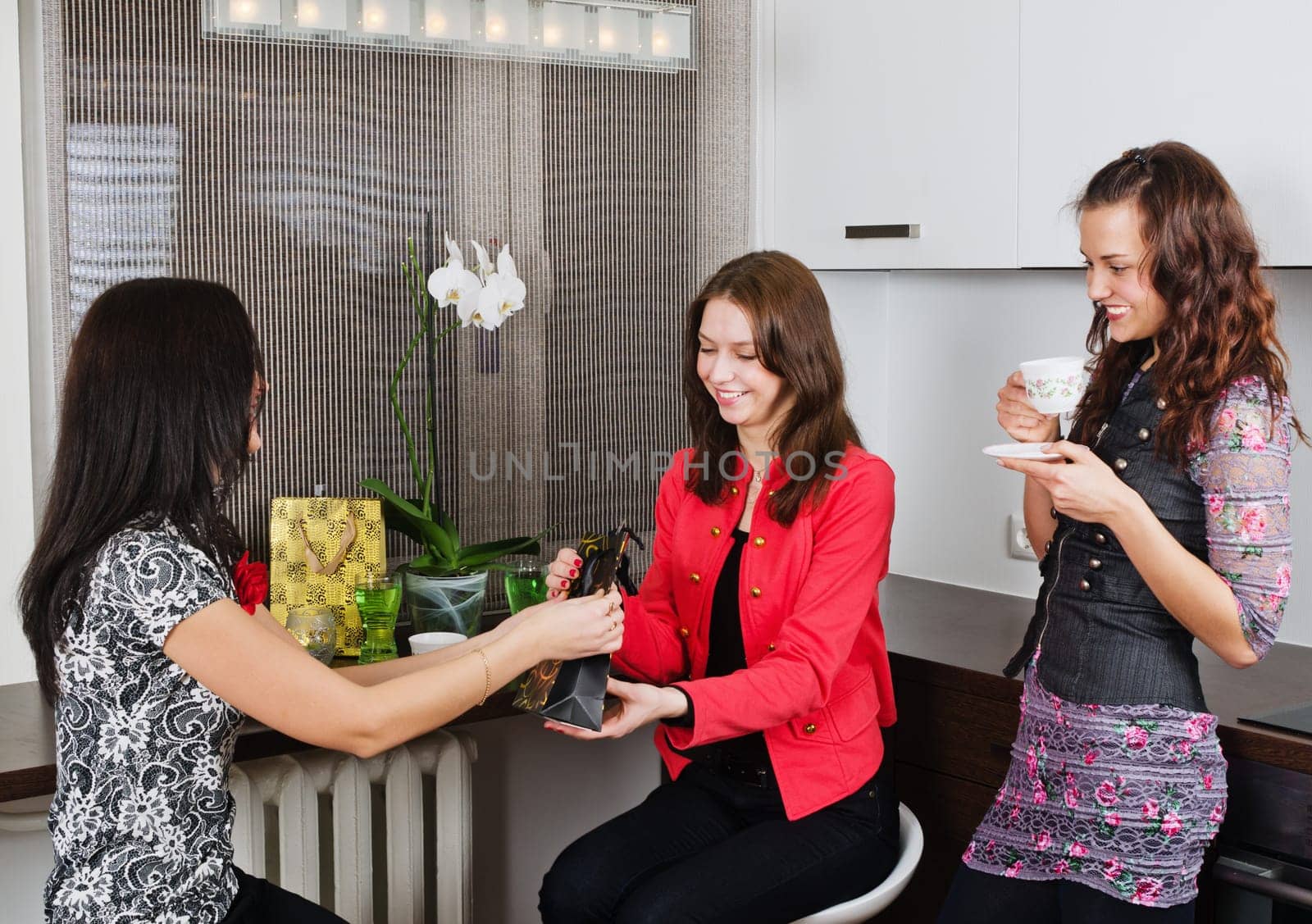 Three young beautiful women drink tea  at a birthday