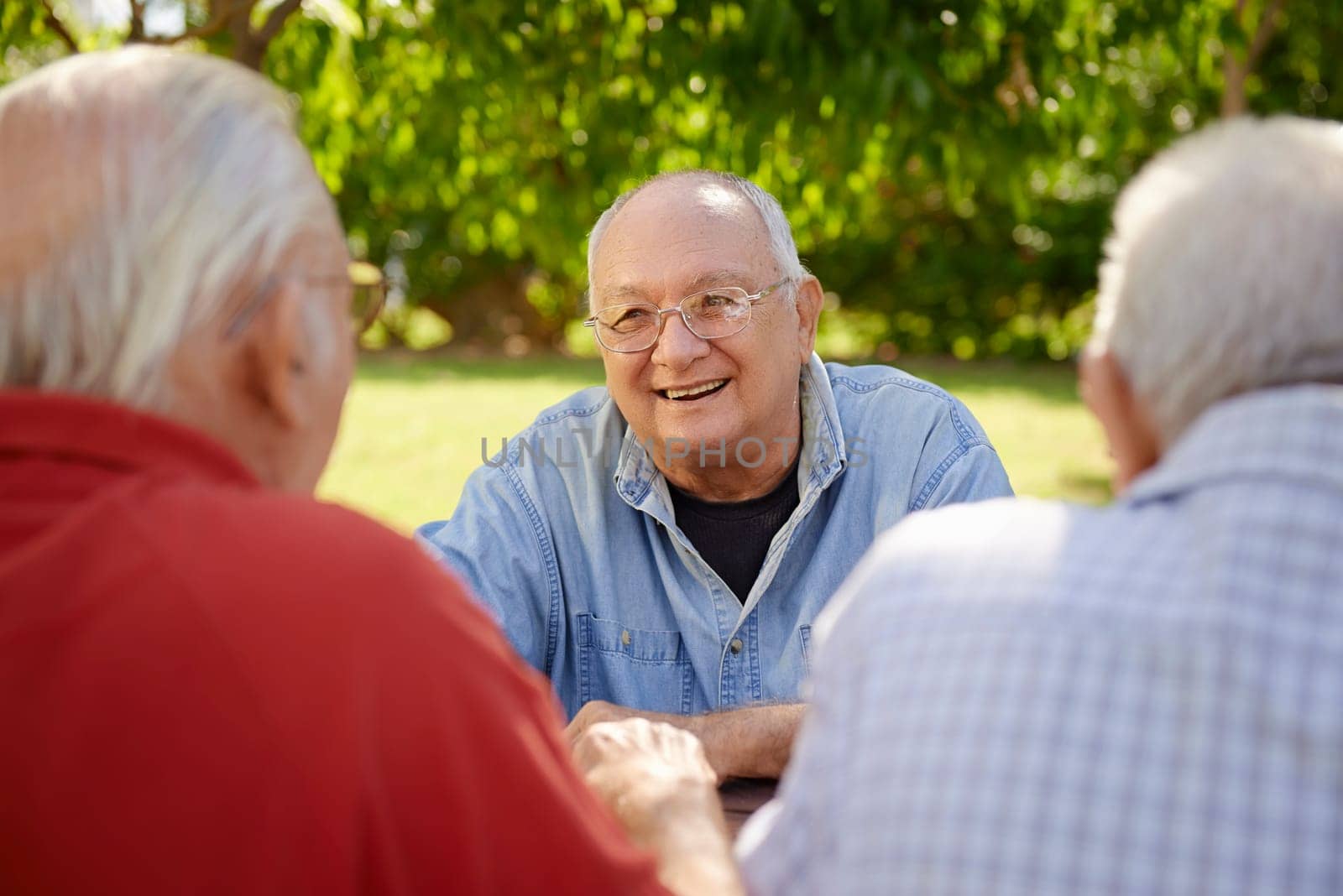 Active retired senior people, old friends and leisure, group of four elderly men having fun, laughing and talking in city park. Waist up