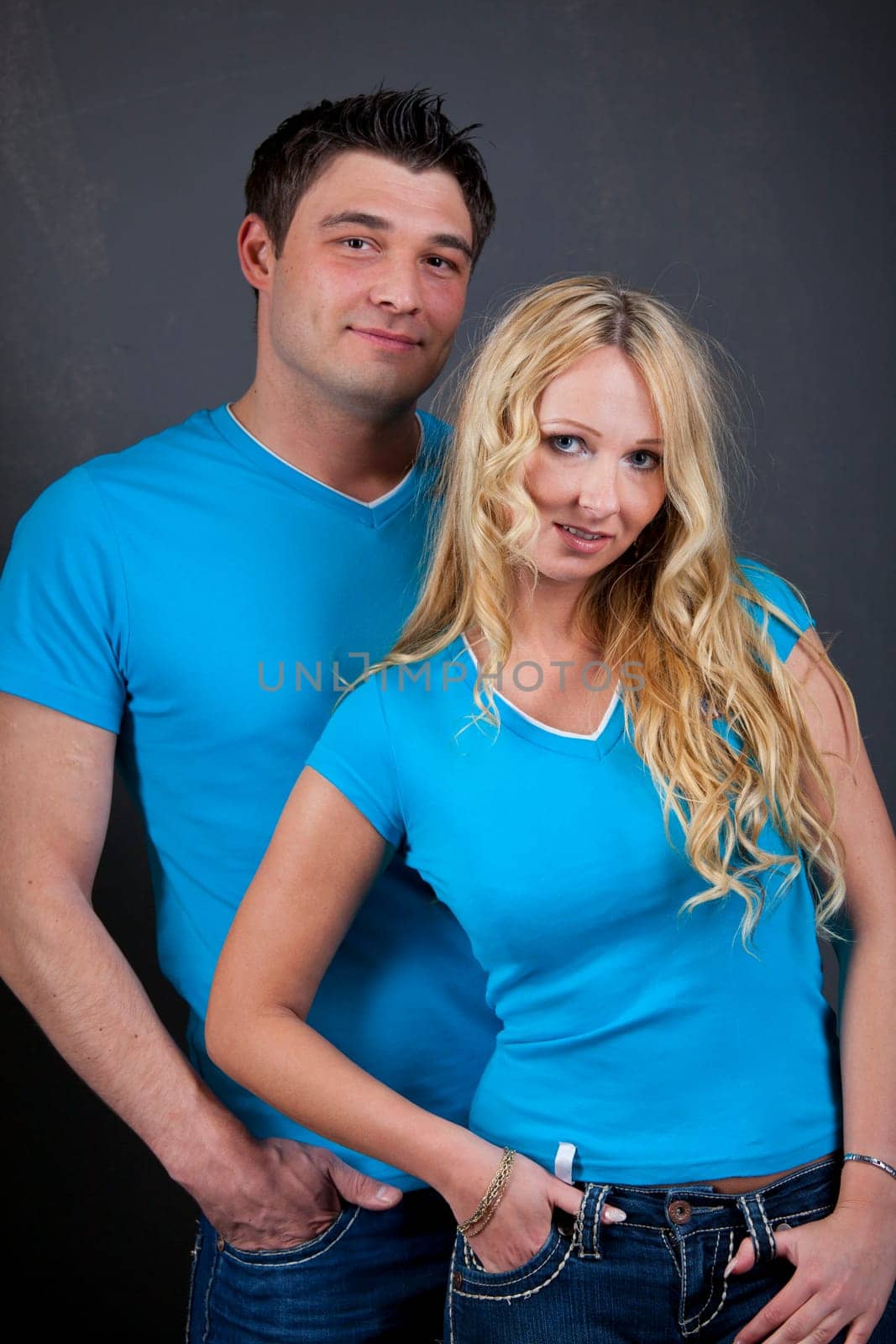 Studio Portrait Of Young Couple in the same look over grey background