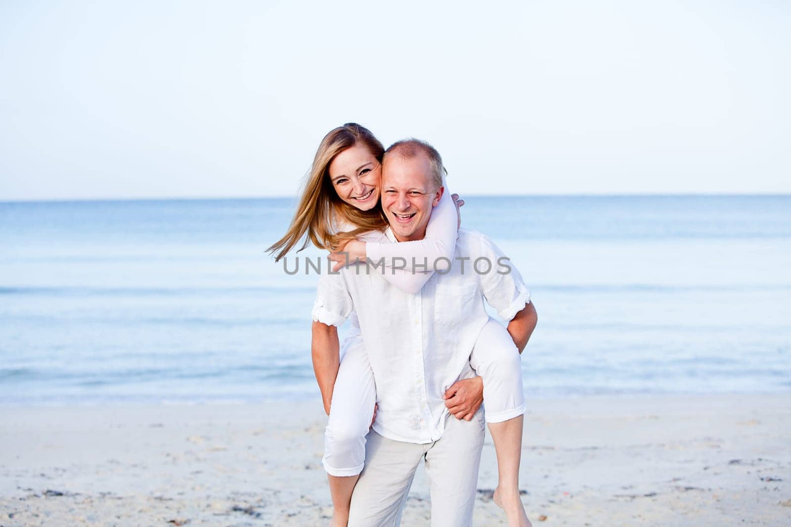 Young happy couple in love having fun on the beach in summer