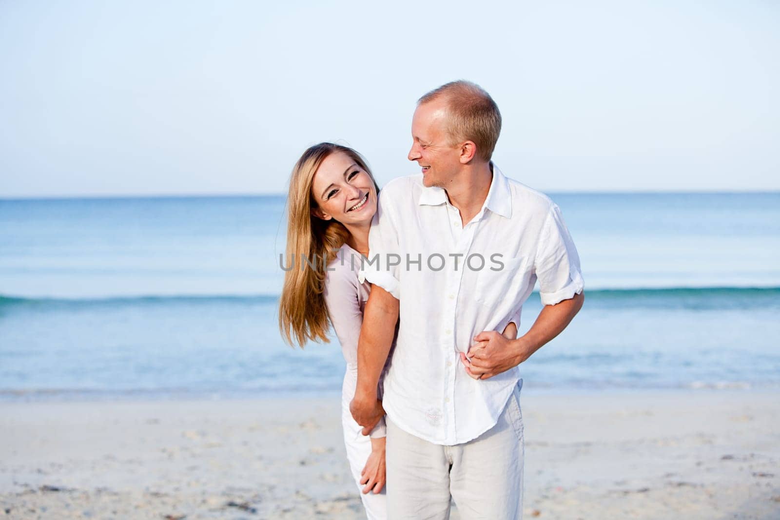 Young happy couple in love having fun on the beach in summer