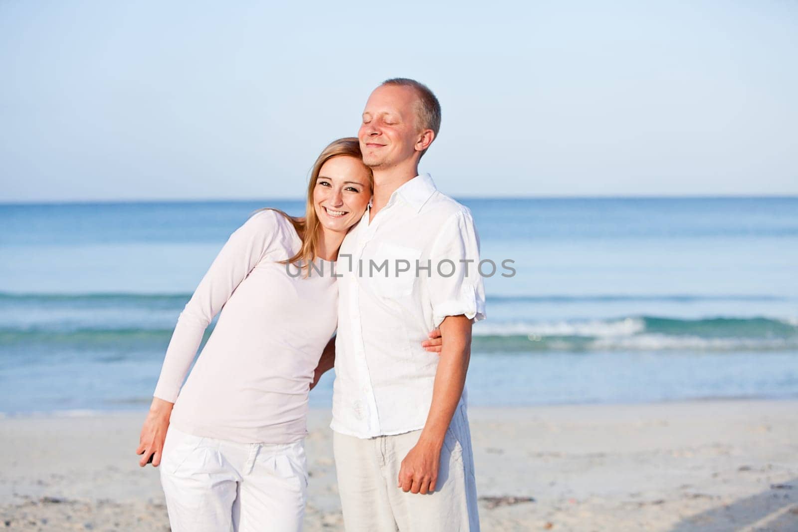 Young happy couple in love having fun on the beach in summer