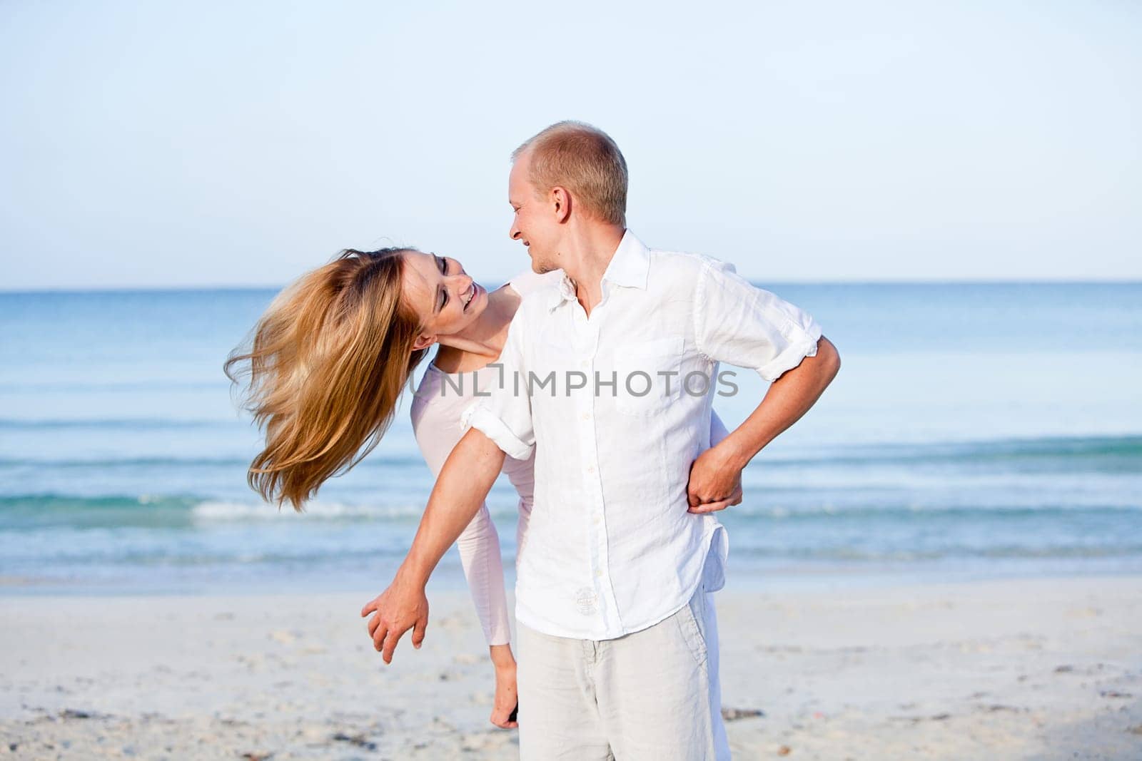 Young happy couple in love having fun on the beach in summer
