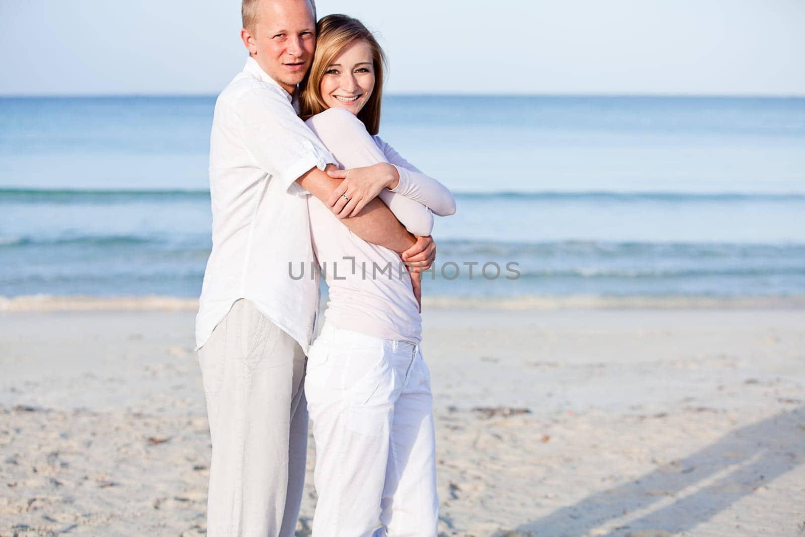 Young happy couple in love having fun on the beach in summer