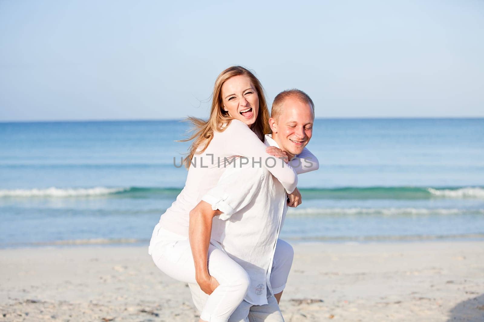 Young happy couple in love having fun on the beach in summer