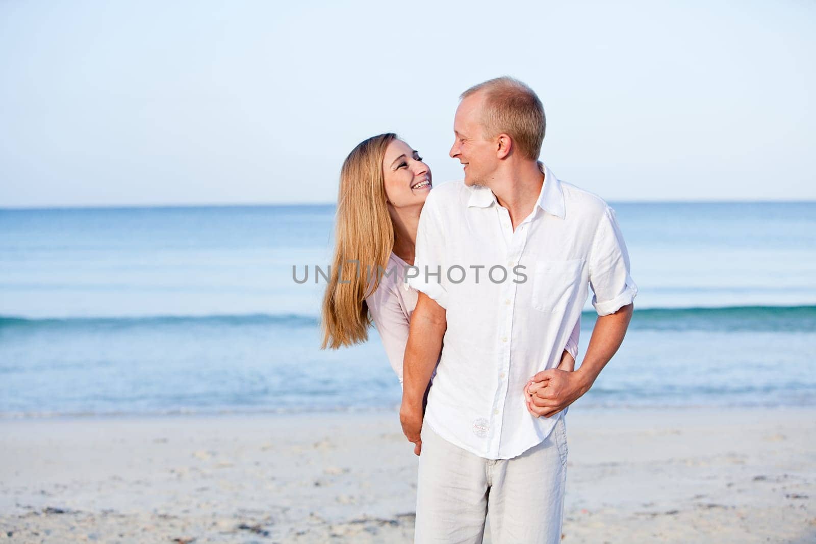 Young happy couple in love having fun on the beach in summer