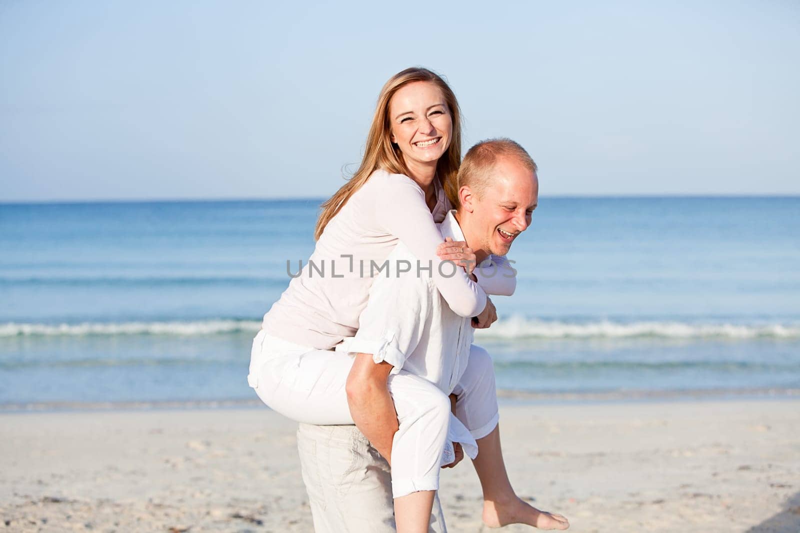 Young happy couple in love having fun on the beach in summer