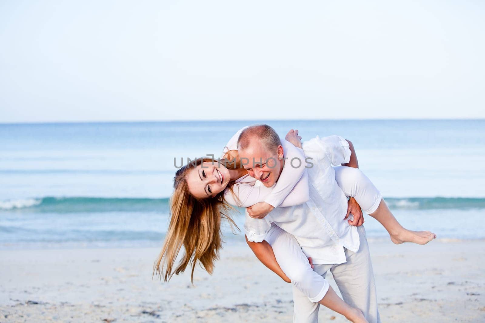 Young happy couple in love having fun on the beach in summer