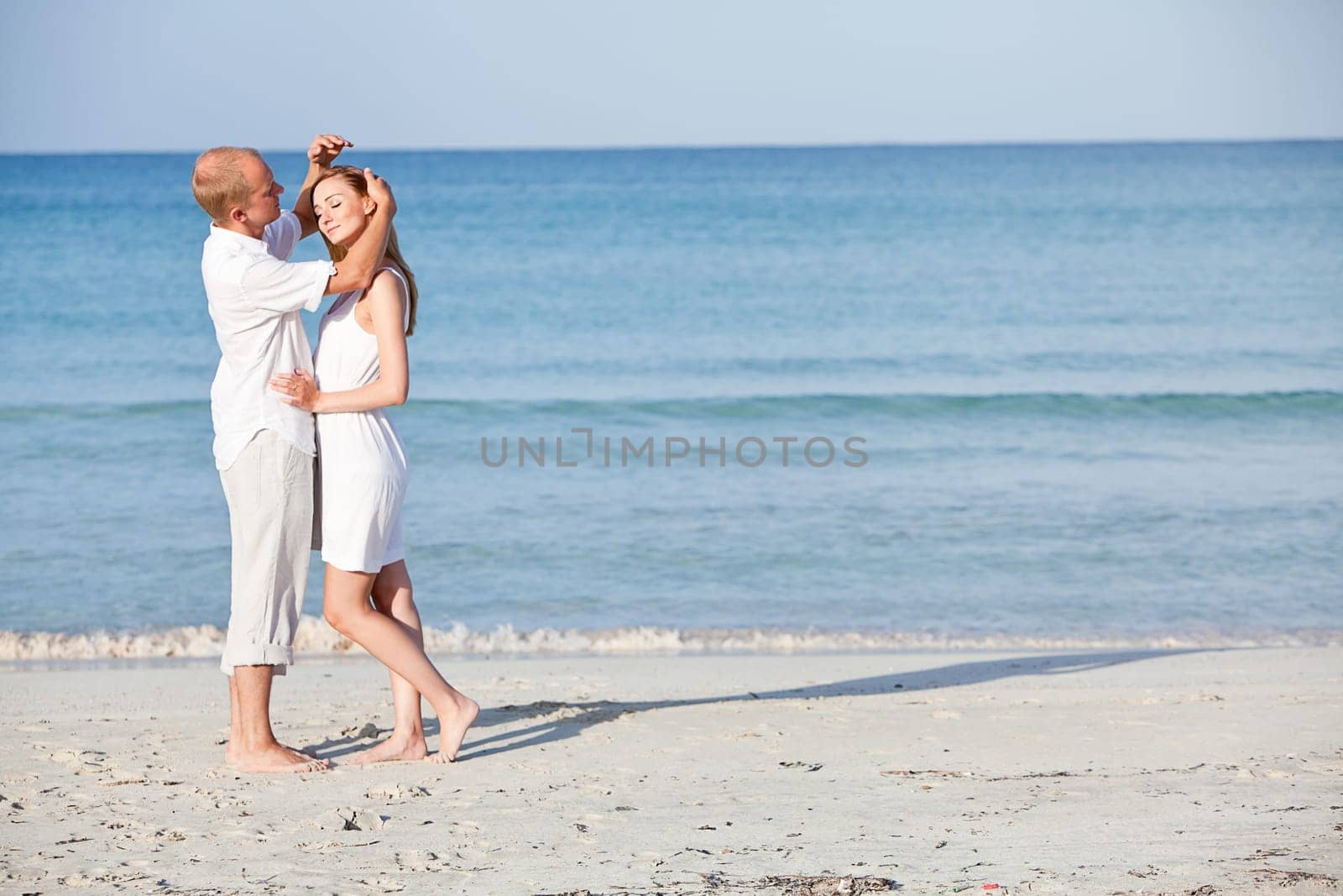 Young happy couple in love having fun on the beach in summer