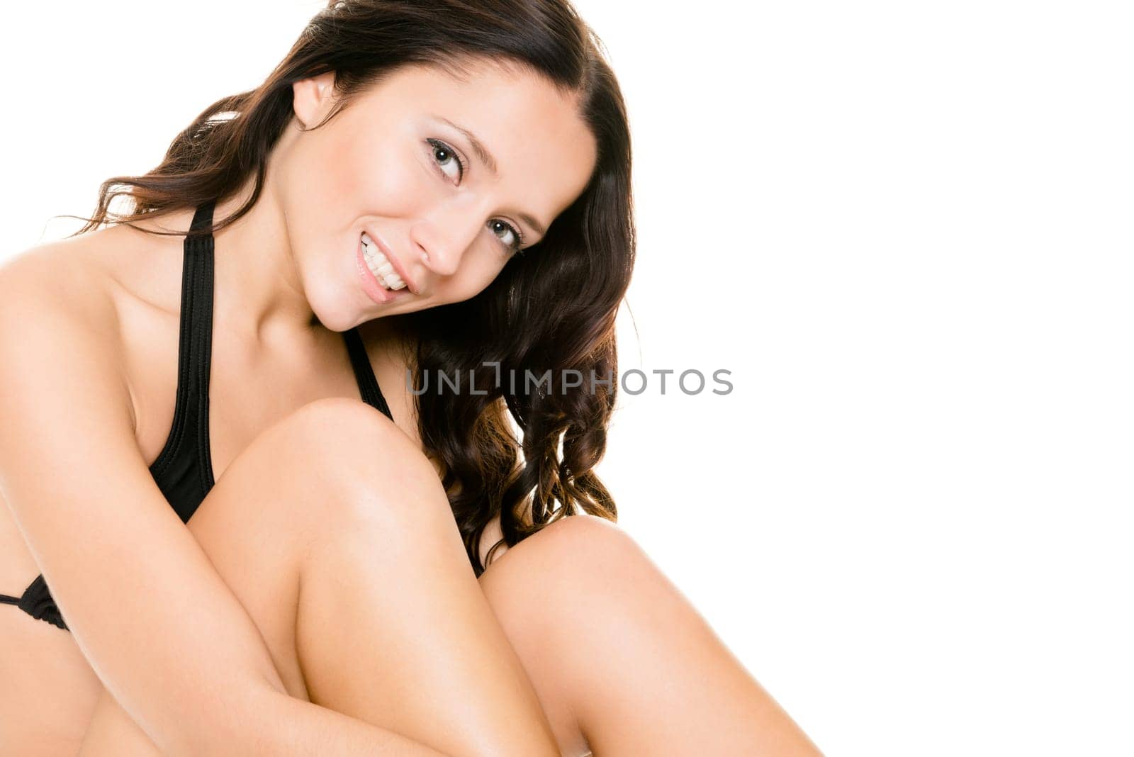 Young woman with black bikini sitting in front of white background