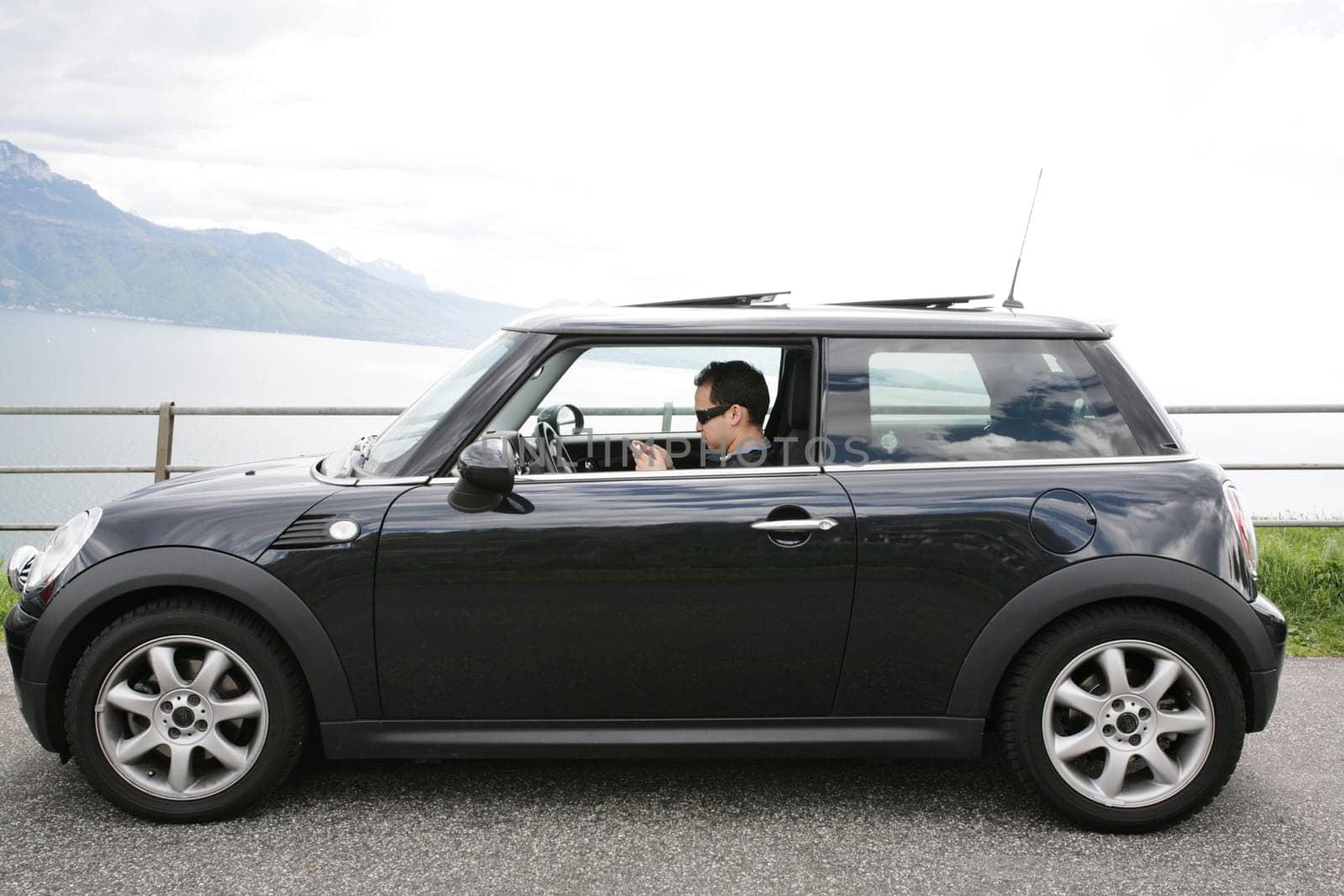 Young man in his fancy car chatting with his device up the hills