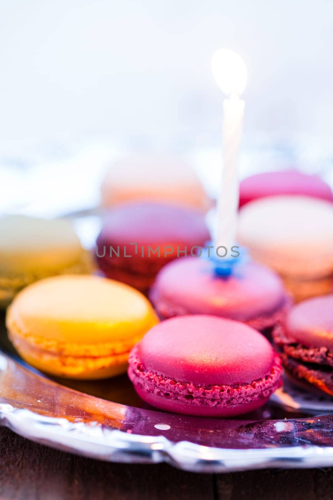 Closeup of macaroons with candle on decorative silver tray