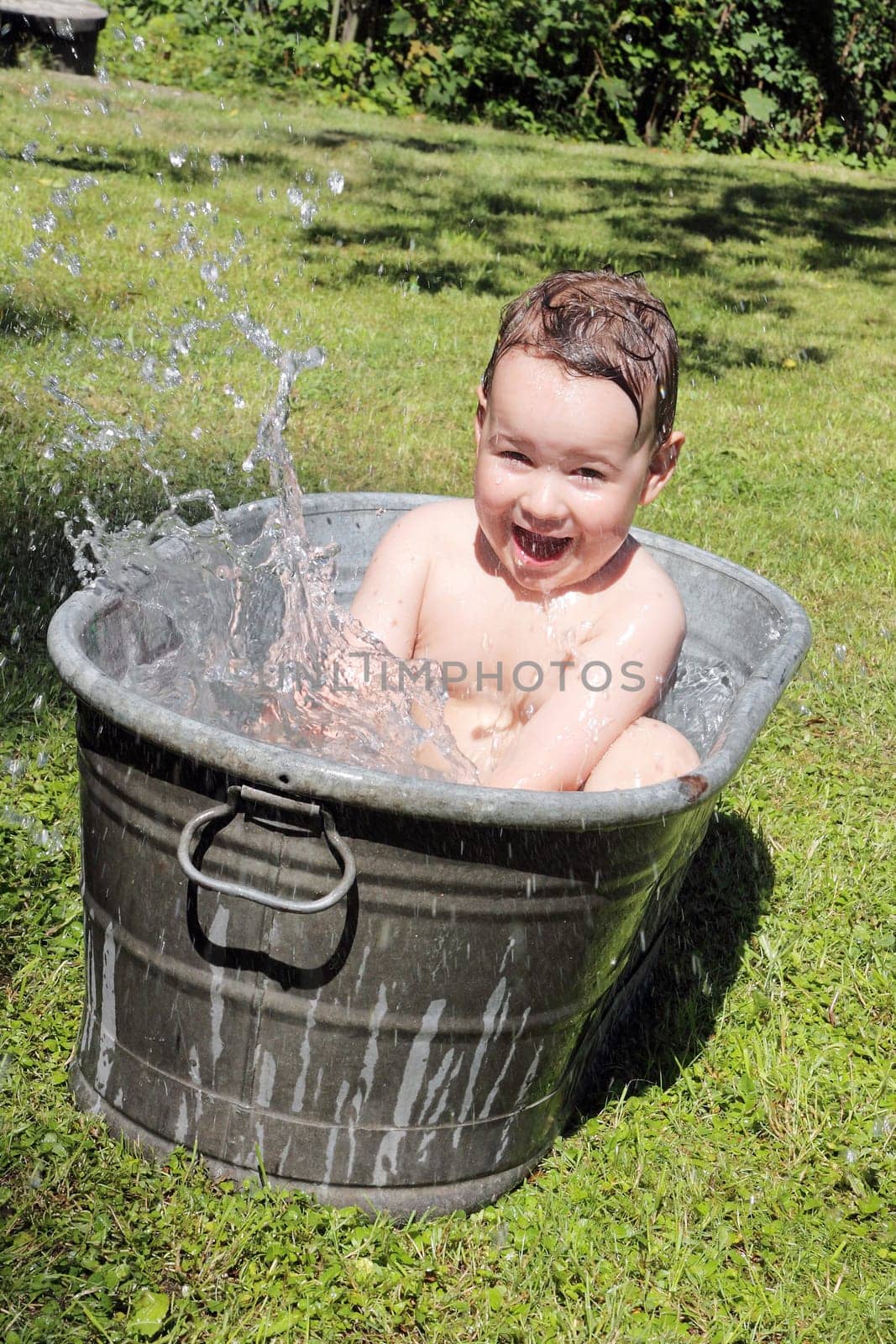 joy caucasian child bathing outdoors in bath with water drops