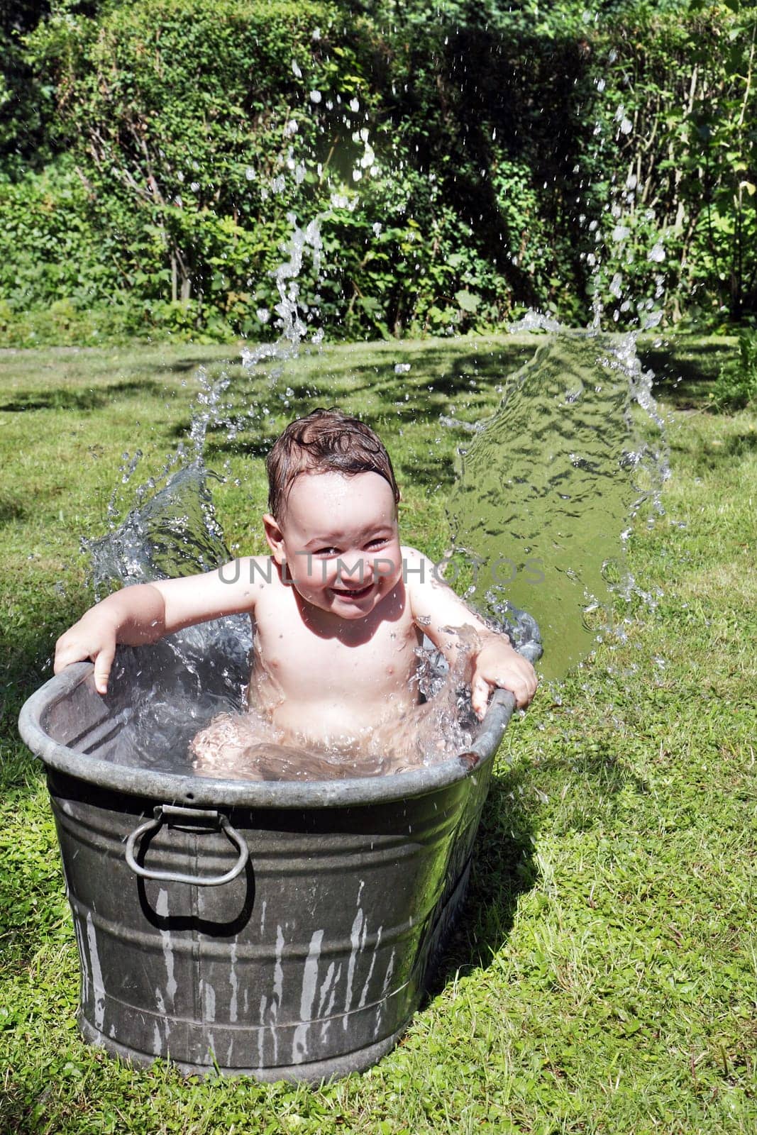 joy caucasian child bathing outdoors in bath with water drops