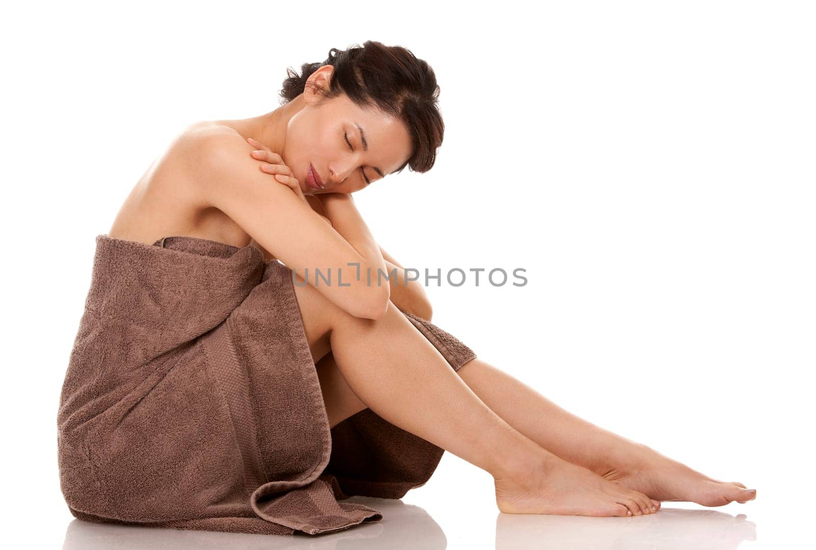 beautiful asian brunette wearing brown towel on white background