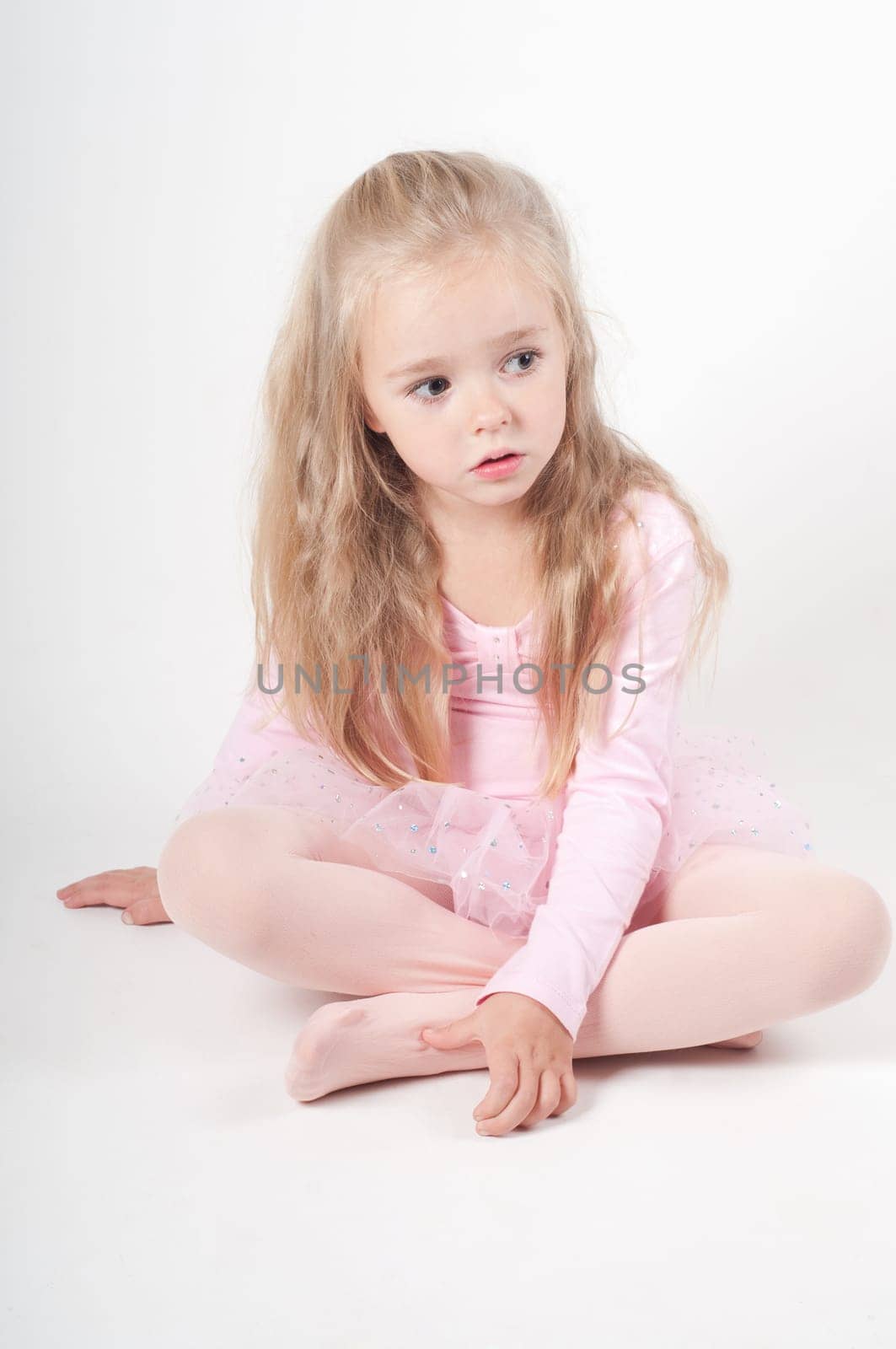 Studio shot of ballet dancer girl sitting on the floor