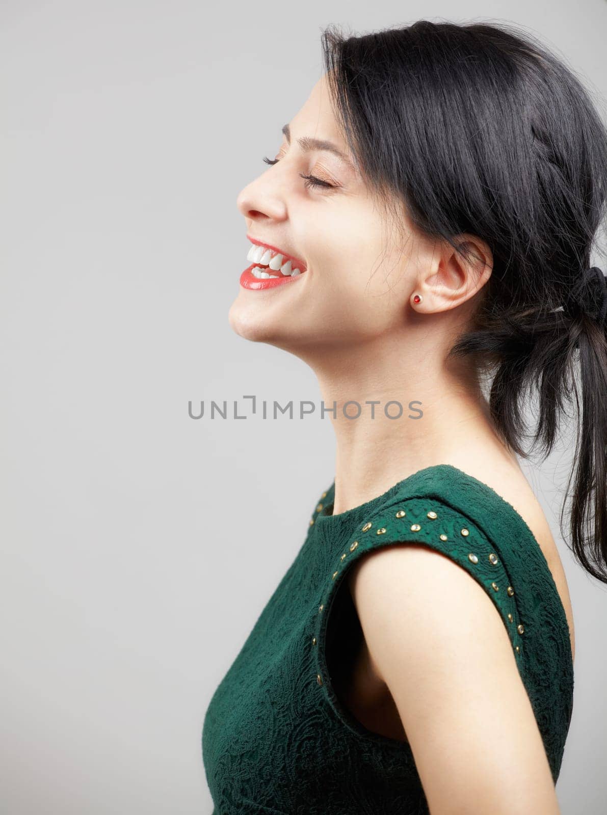 Portrait of a beautiful young woman wearing a green elegant dress over grey background.